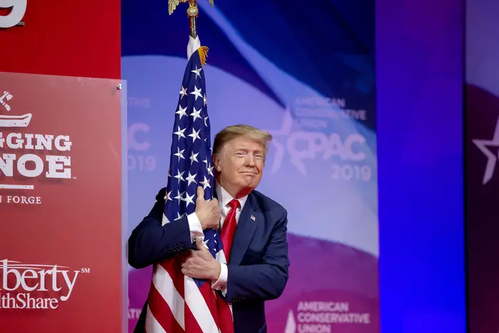 This is a photo of Donald Trump hugging an American flag.